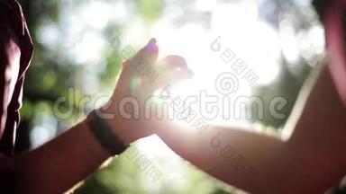 在绿色的夏日森林里牵着相爱的情侣的手。 <strong>太阳光束</strong>。